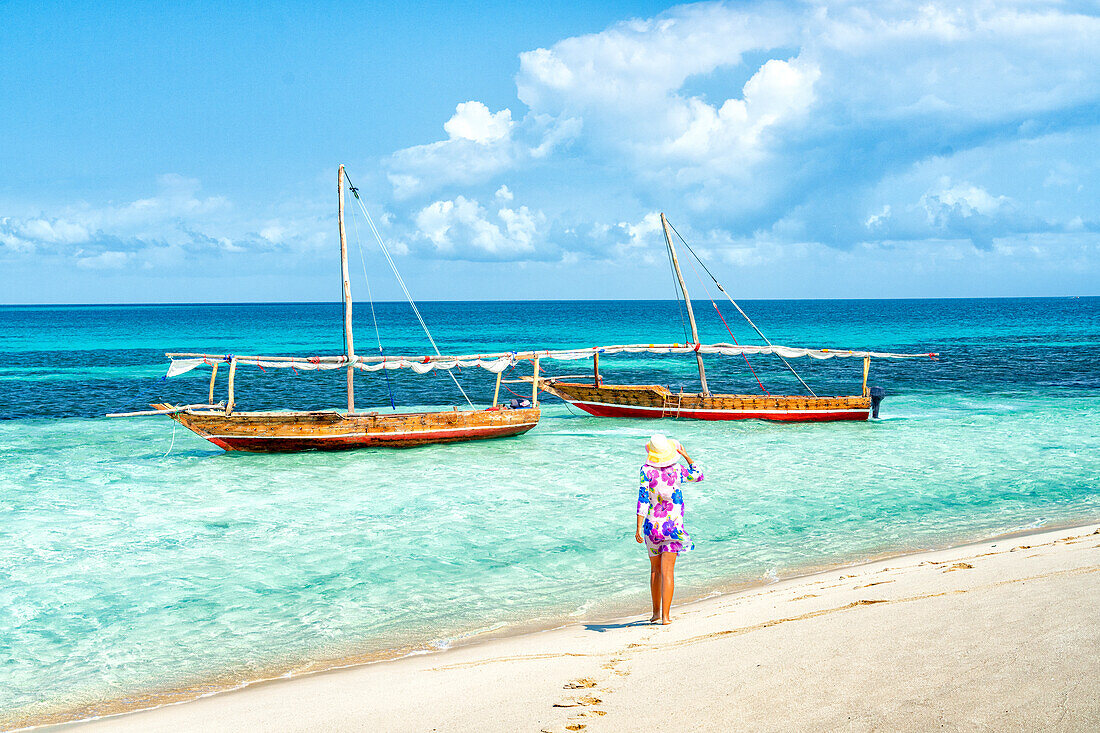 Cheerful woman with hat admiring the crystal clear sea standing on a beach, Kwale Island, Zanzibar, Tanzania, East Africa, Africa