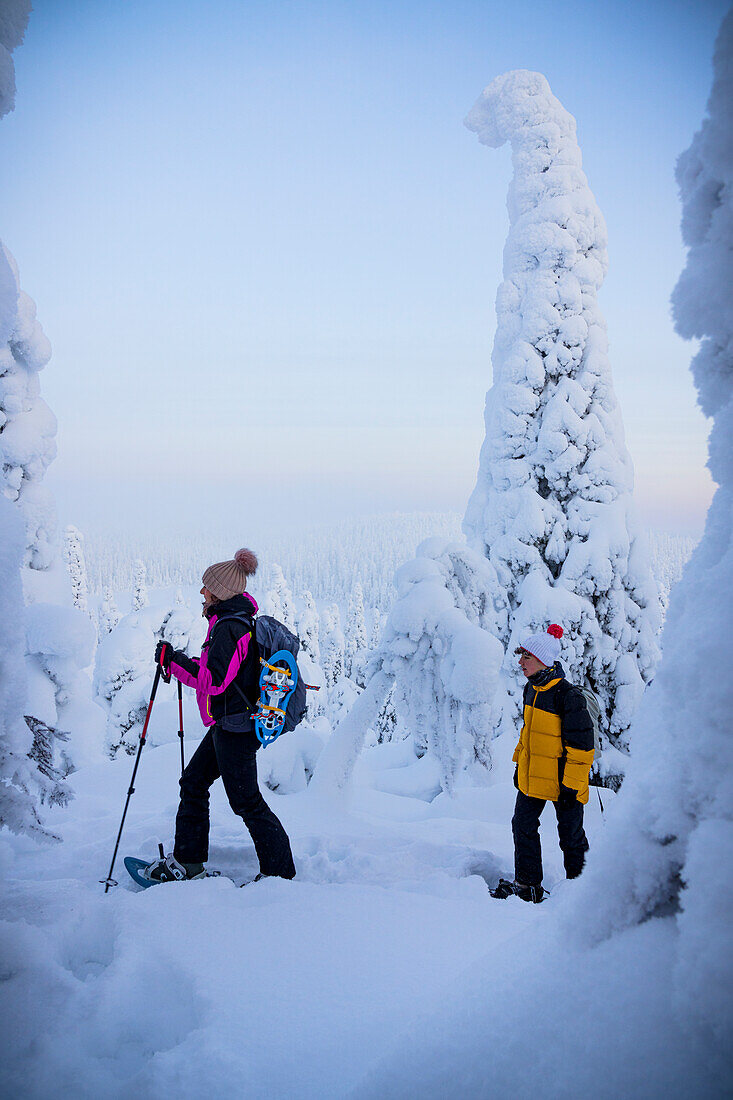 Cheerful mother with son snowshoeing in the frozen forest, Oulanka National Park, Ruka Kuusamo, Lapland, Finland, Europe