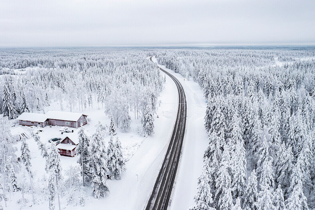 Kurvenreiche Straße durch den gefrorenen verschneiten Wald, Luftaufnahme, Lappland, Finnland, Europa