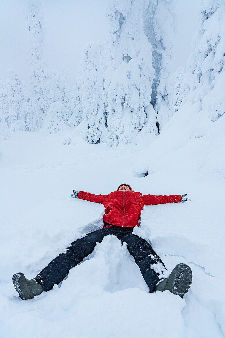 Fröhliche Frau lächelnd im Schnee liegend, Lappland, Finnland, Europa