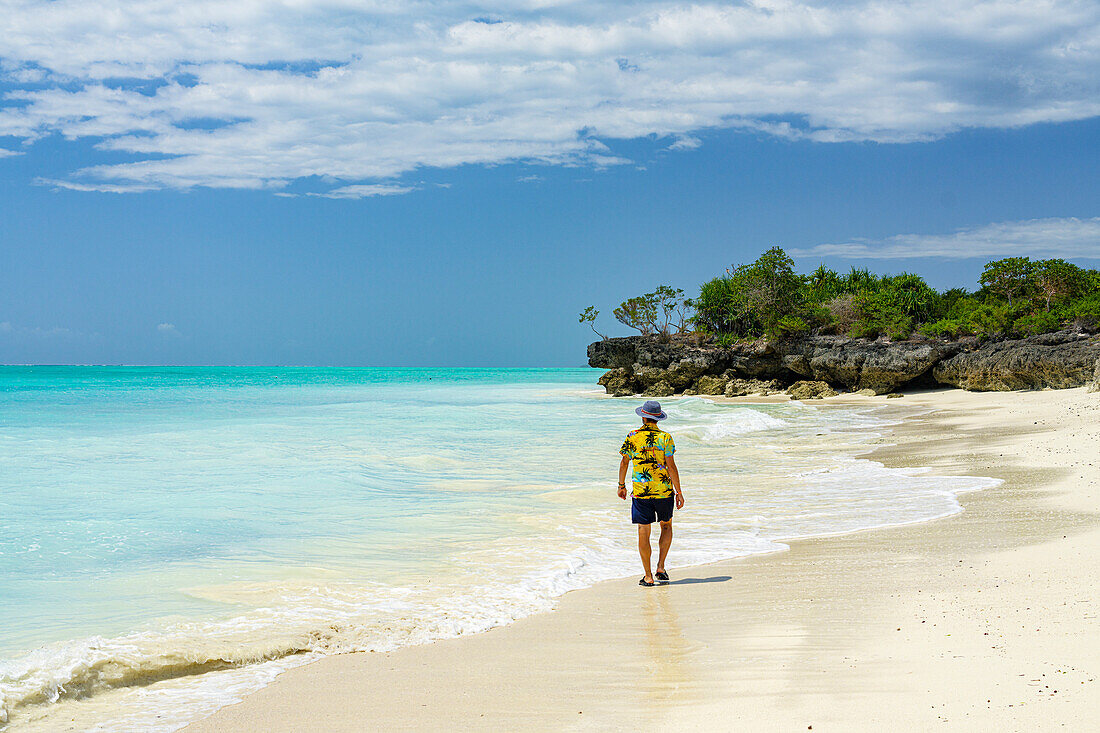 Mittlerer erwachsener Mann, der am leeren Sandstrand spazieren geht, Nungwi, Sansibar, Tansania, Ostafrika, Afrika