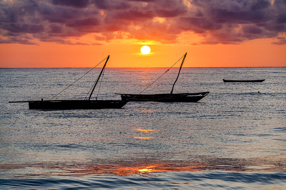 Cloudy sky at sunrise over silhouettes of boats moored in the sea, Jambiani, Zanzibar, Tanzania, East Africa, Africa