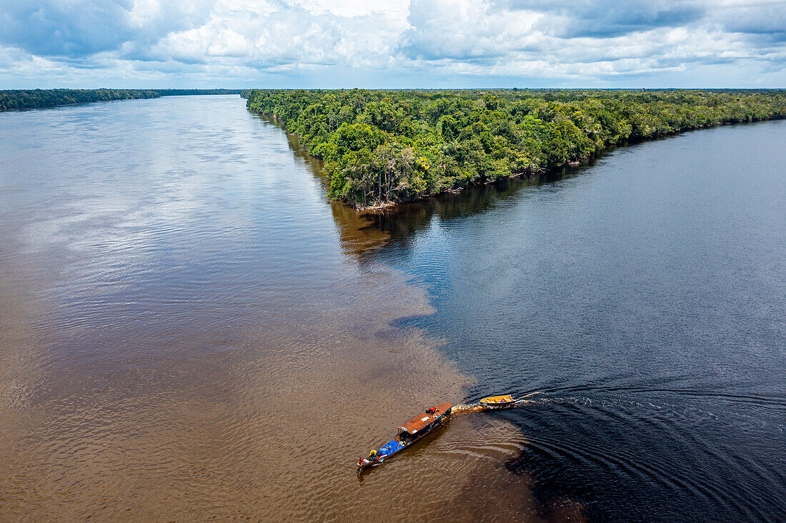 Little boat on the meeting point of the Casiquiare River and black Pasimoni River, in the deep south of Venezuela, South America