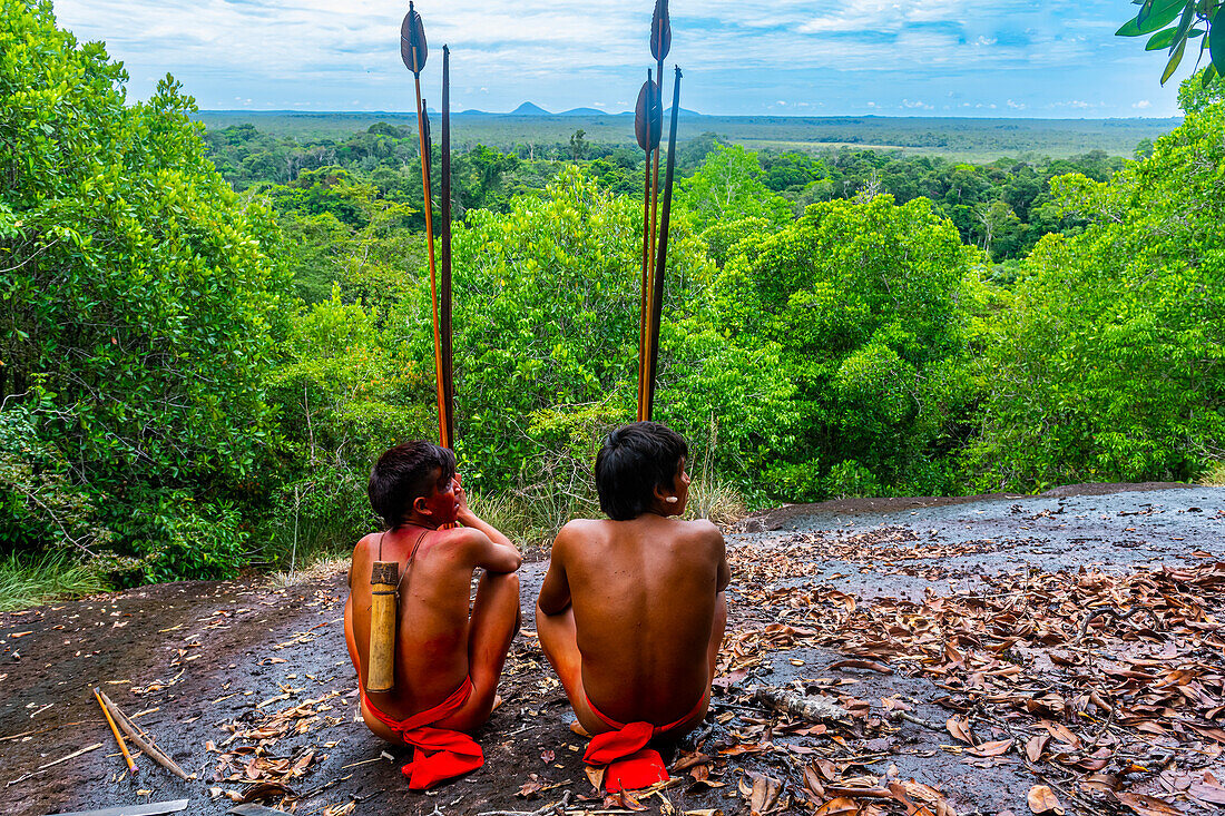 Yanomami-Stammesangehörige sitzen auf einem riesigen Felsen im Dschungel, Südvenezuela, Südamerika