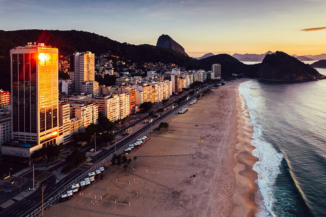 Drohnenaufnahme des Leme Beach im Copacabana-Viertel bei Sonnenaufgang mit dem ikonischen Zuckerhut im Hintergrund, UNESCO-Weltkulturerbe, Rio de Janeiro, Brasilien, Südamerika