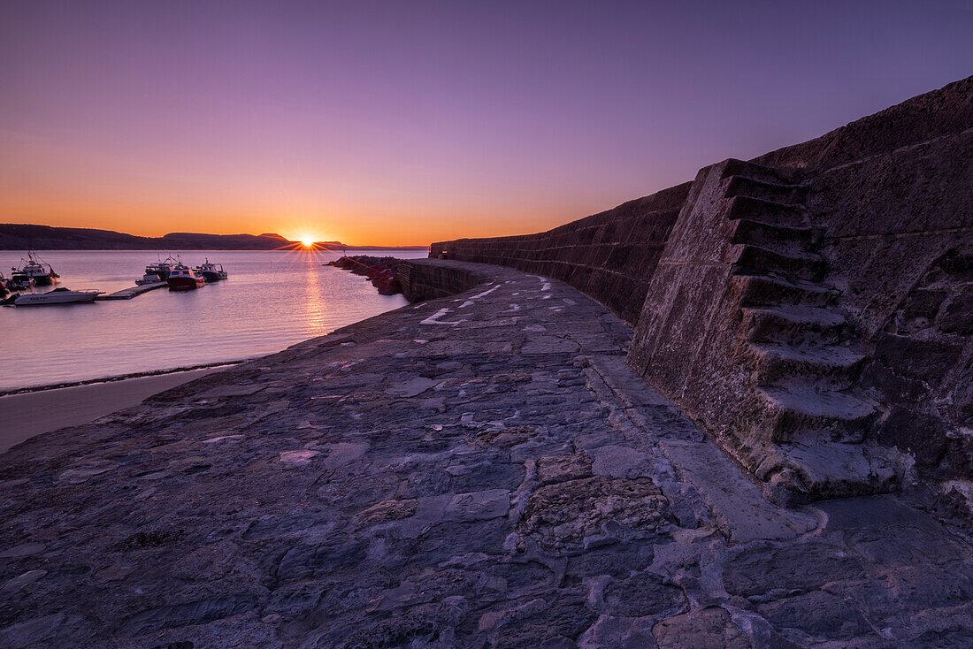 Sonnenaufgang an der als The Cobb bekannten Hafenmauer in Lyme Regis, Dorset, England, Vereinigtes Königreich, Europa