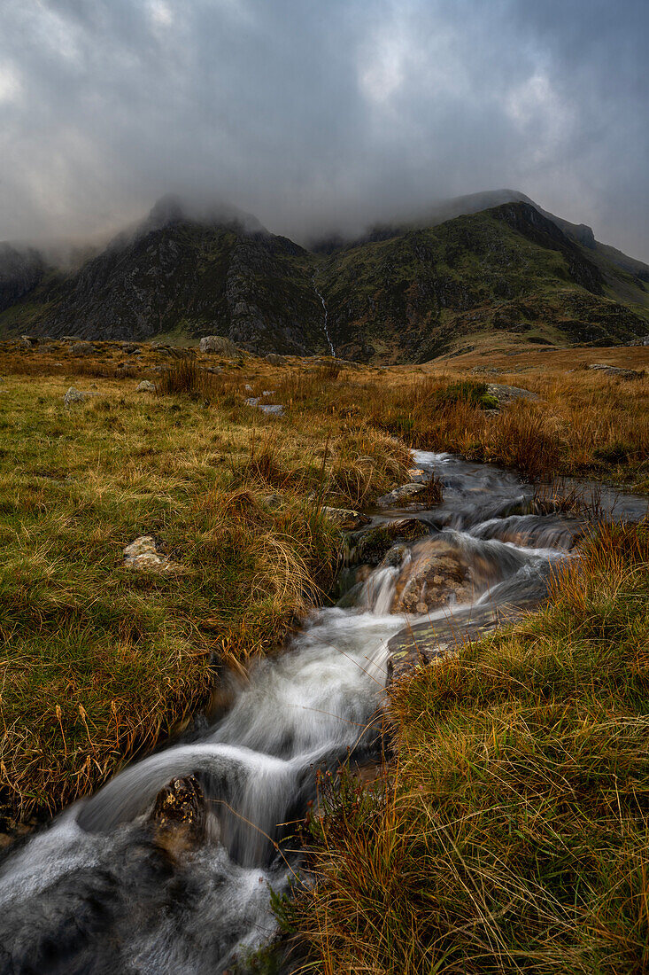 Kaskadenförmiges Wasser im Nant Ffrancon-Tal vor der Kulisse der Berge, Snowdonia, Wales, Vereinigtes Königreich, Europa