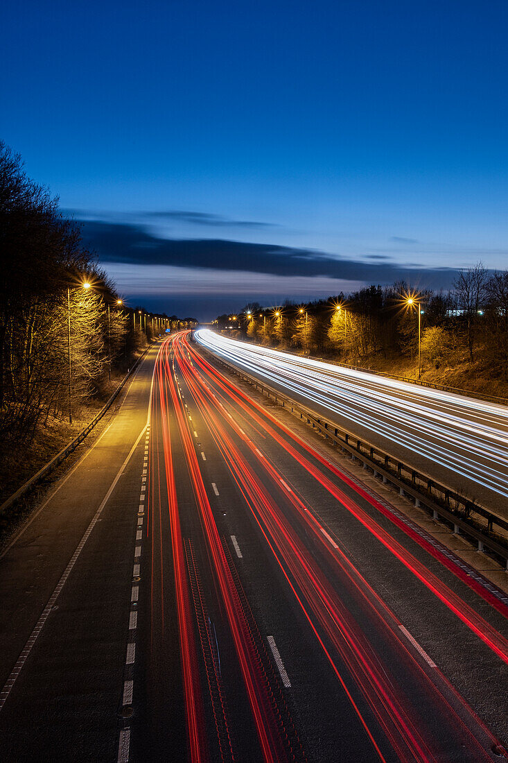 Die Autobahn M56 bei Nacht mit Verkehrsspuren in westlicher Richtung, Cheshire, England, Vereinigtes Königreich, Europa