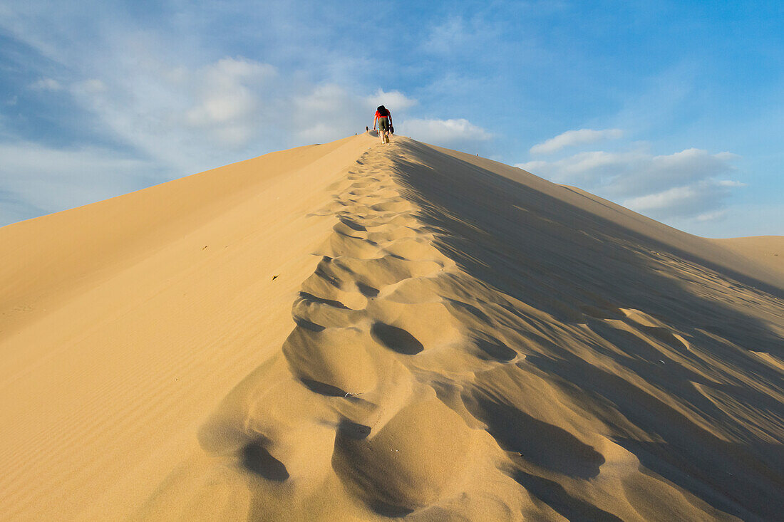 People walking up sand dune, Huacachina, Peru, South America