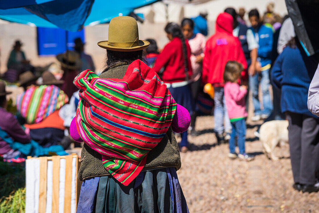 Peruvian woman carrying colorful bag on her back, Pisaq market, Sacred Valley, Cusco, Peru, South America