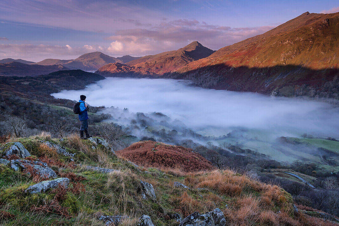 Wanderer mit Blick auf den Gipfel des Yr Aran und das nebelverhangene Nant Gwynant Valley, Nant Gwynant, Eryri, Snowdonia National Park, Nordwales, Vereinigtes Königreich, Europa