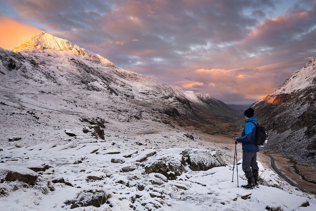 Wanderer mit Blick auf Crib Goch und den Llanberis Pass in der Morgendämmerung im Winter, Snowdonia National Park, Eryri, Nordwales, Vereinigtes Königreich, Europa