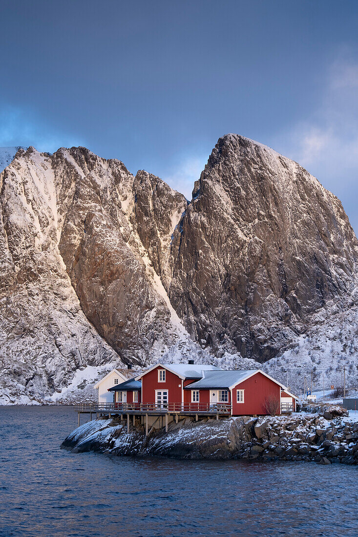 Rote norwegische Rorbuerhütten und der Berg Festhaeltinden im Winter, Reine, Gemeinde Moskenes, Landkreis Nordland, Lofoten, Norwegen, Skandinavien, Europa