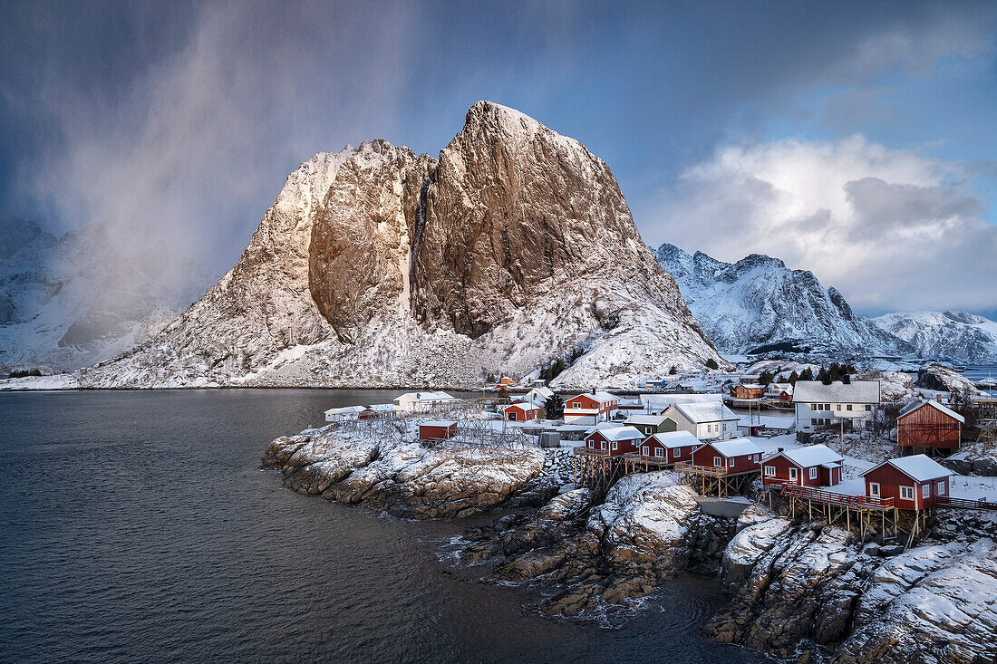 Rote norwegische Rorbuerhütten und der Berg Festhaeltinden im Winter, Hamnoy, Kommune Moskenes, Landkreis Nordland, Lofoten, Norwegen, Skandinavien, Europa