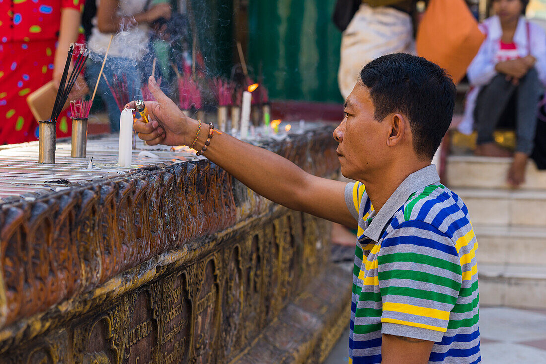 Mann zündet Kerze an, Shwedagon-Pagode, Yangon, Myanmar (Birma), Asien
