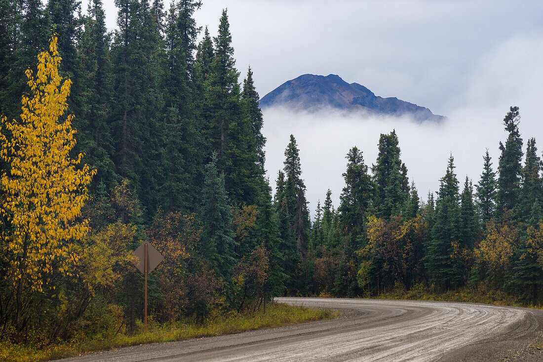 Berg, der sich über tief hängenden Wolken am Denali Parks Highway im Herbst erhebt, in der Nähe des Teklanika River Campground, Denali National Park, Alaska, Vereinigte Staaten von Amerika, Nordamerika