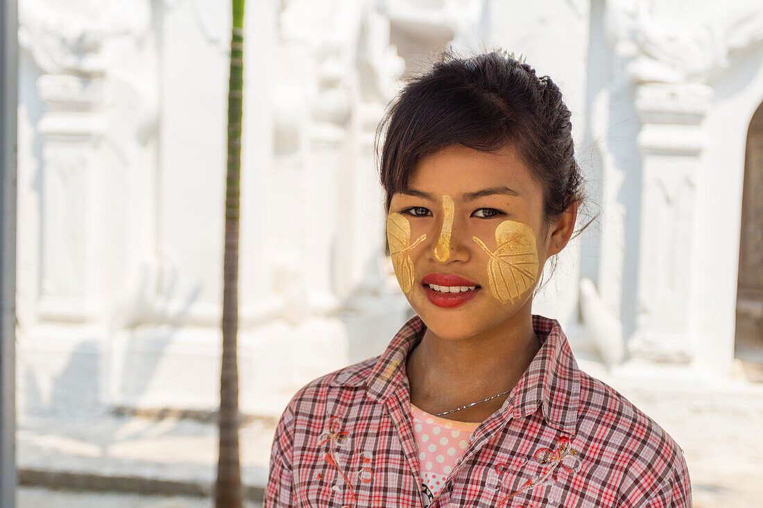 Junge birmanische Frau mit Blättern, die mit Thanaka auf ihre Wangen gemalt sind, Sandamuni-Pagode, Mandalay, Myanmar (Birma), Asien