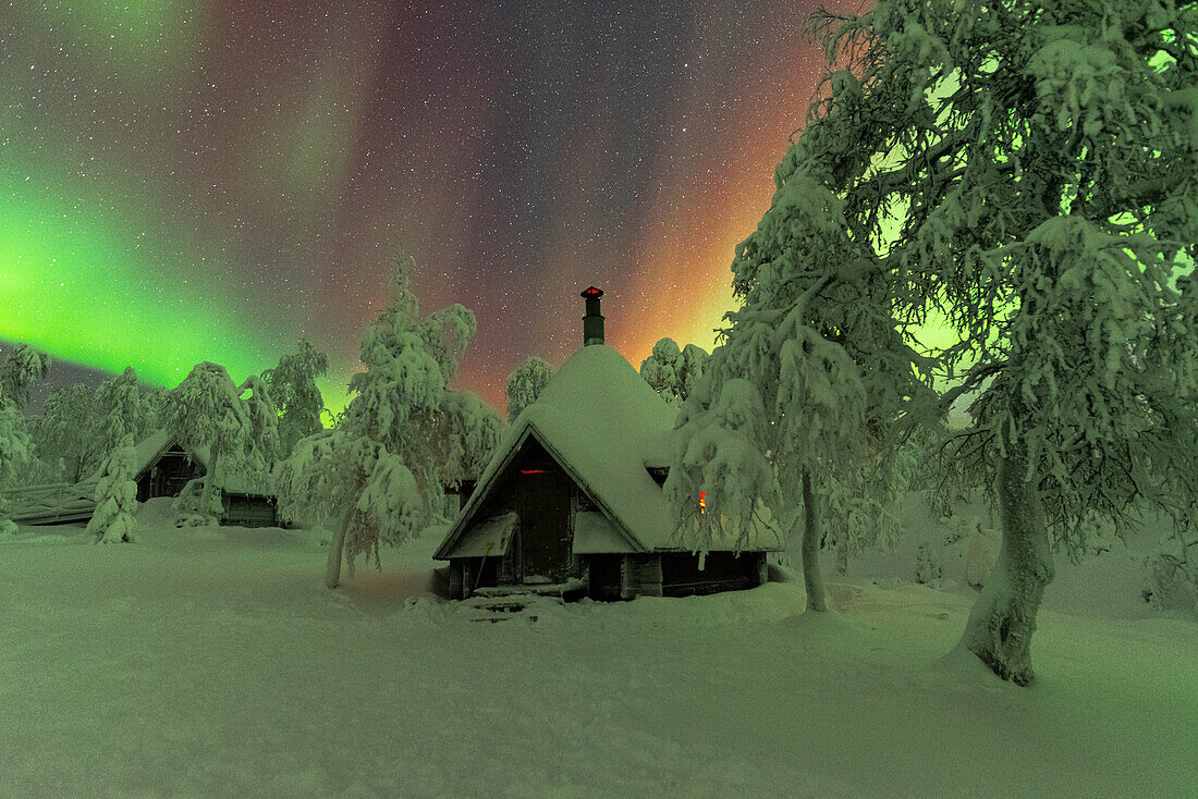 Hütten im verschneiten Wald unter den Nordlichtern (Aurora Borealis), Pallas-Yllastunturi-Nationalpark, Muonio, Lappland, Finnland, Europa