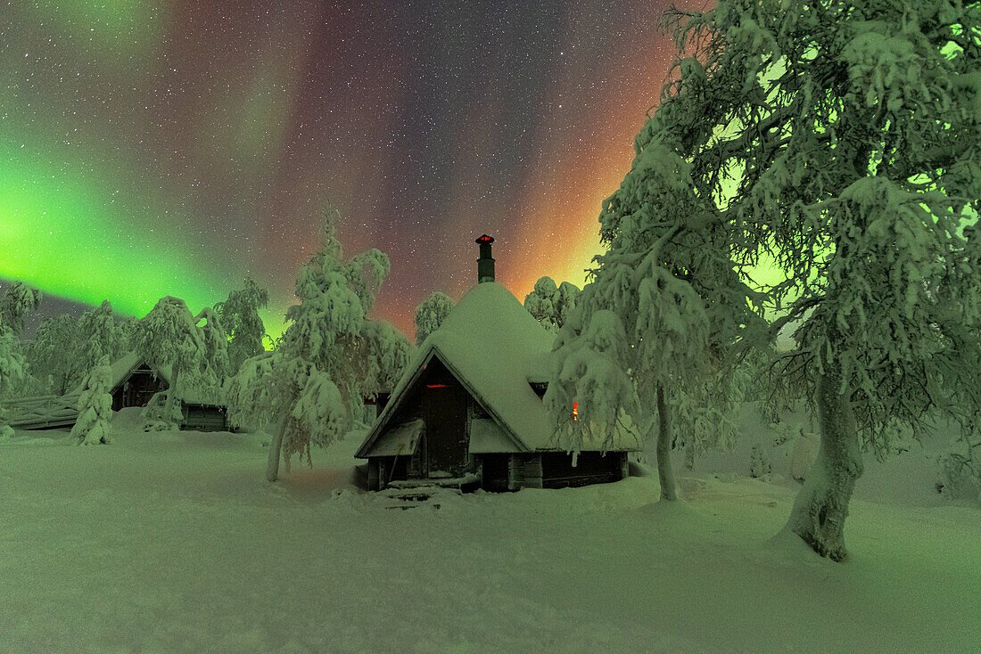 Huts in the snowy wood under the Northern Lights (Aurora Borealis), Pallas-Yllastunturi National Park, Muonio, Lapland, Finland, Europe