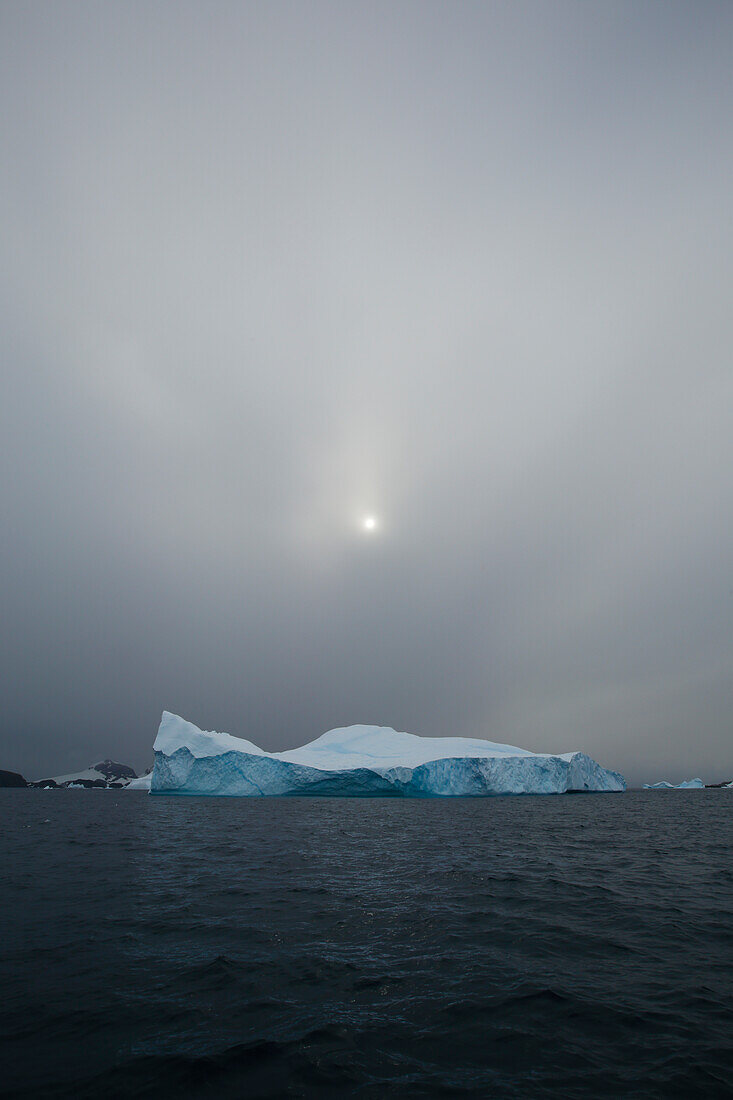 Obscured sun hovering over iceberg, Antarctic Peninsula, Antarctica, Polar Regions