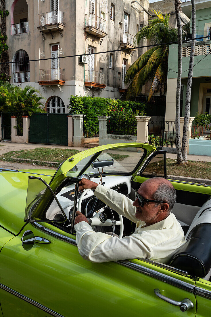 Driver in green open top Chevrolet classic car parked in suburb, Havana, Cuba, West Indies, Caribbean, Central America