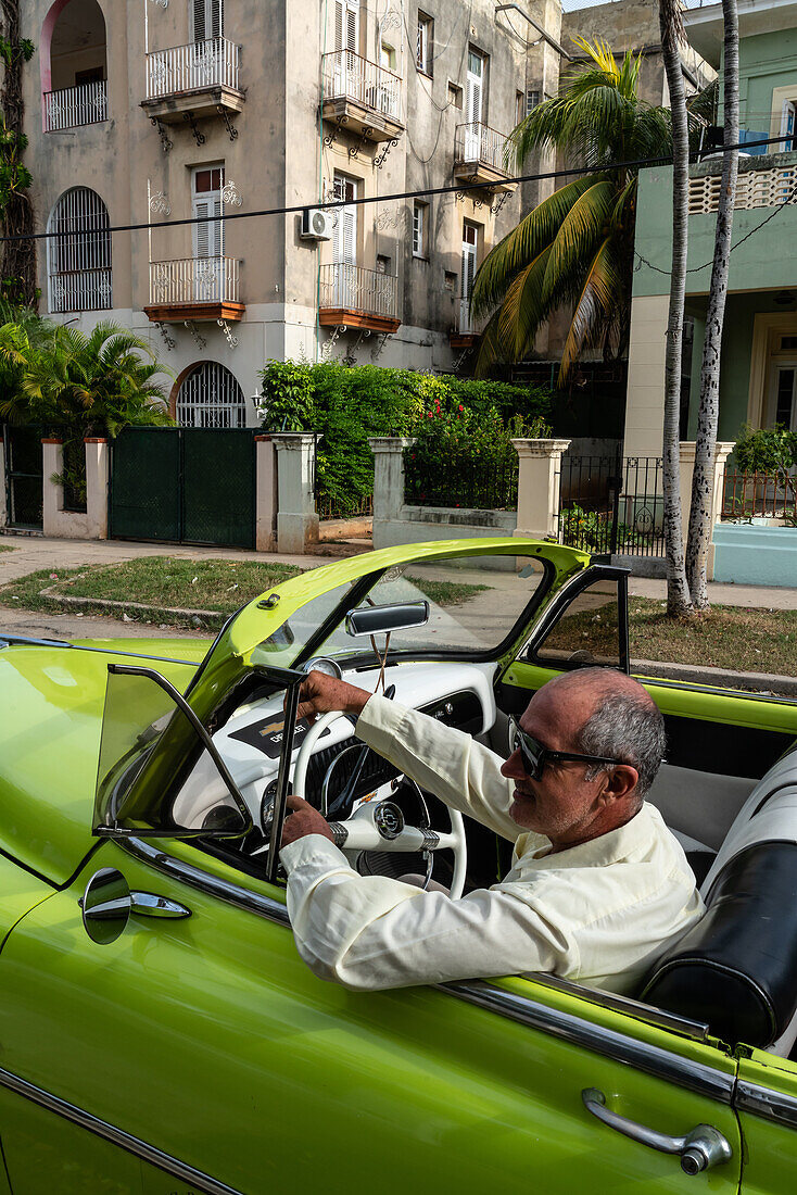 Fahrer in grünem Chevrolet-Oldtimer mit offenem Verdeck, geparkt in einem Vorort, Havanna, Kuba, Westindien, Karibik, Mittelamerika