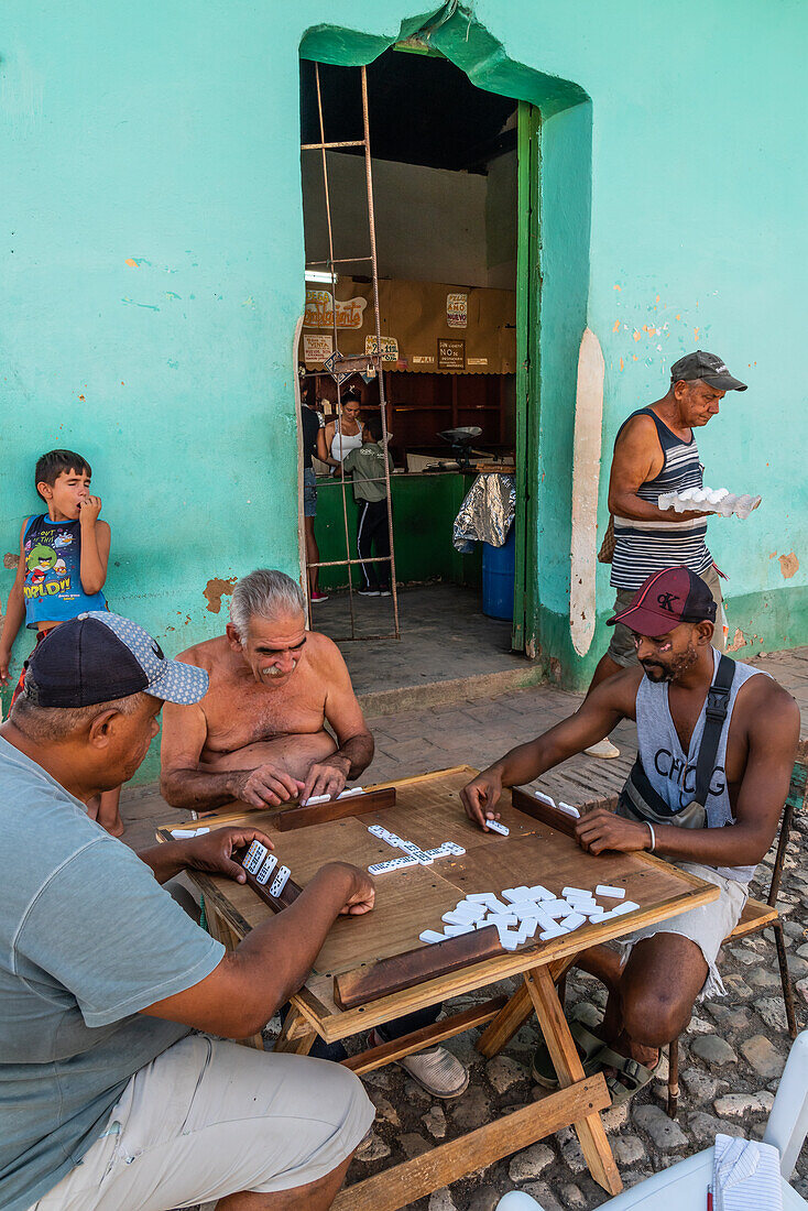 Domino-Spiel im Gange, während ein Mann den Laden an der Ecke mit Eiern verlässt, Trinidad, Kuba, Westindien, Karibik, Mittelamerika