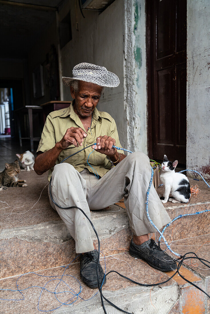 Electrician wiring himself in knots with his cats, Santa Clara, Cuba, West Indies, Caribbean, Central America