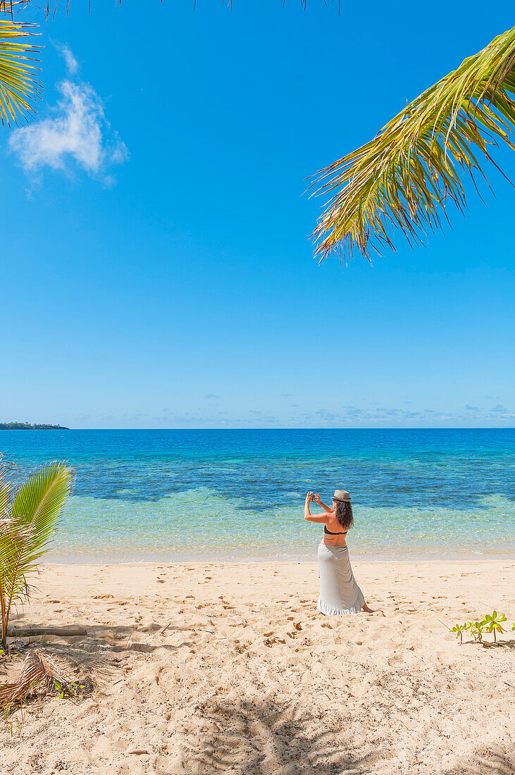 Woman taking photographs on a tropical beach, Drawaqa Island, Yasawa islands, Fiji, South Pacific Islands, Pacific