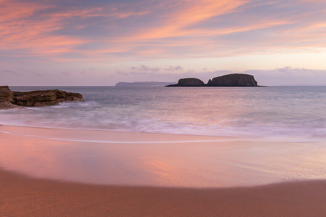 Sunrise over Sheep Island from the sandy shores of Secret Beach at Ballintoy in autumn, County Antrim, Ulster, Northern Ireland, United Kingdom, Europe