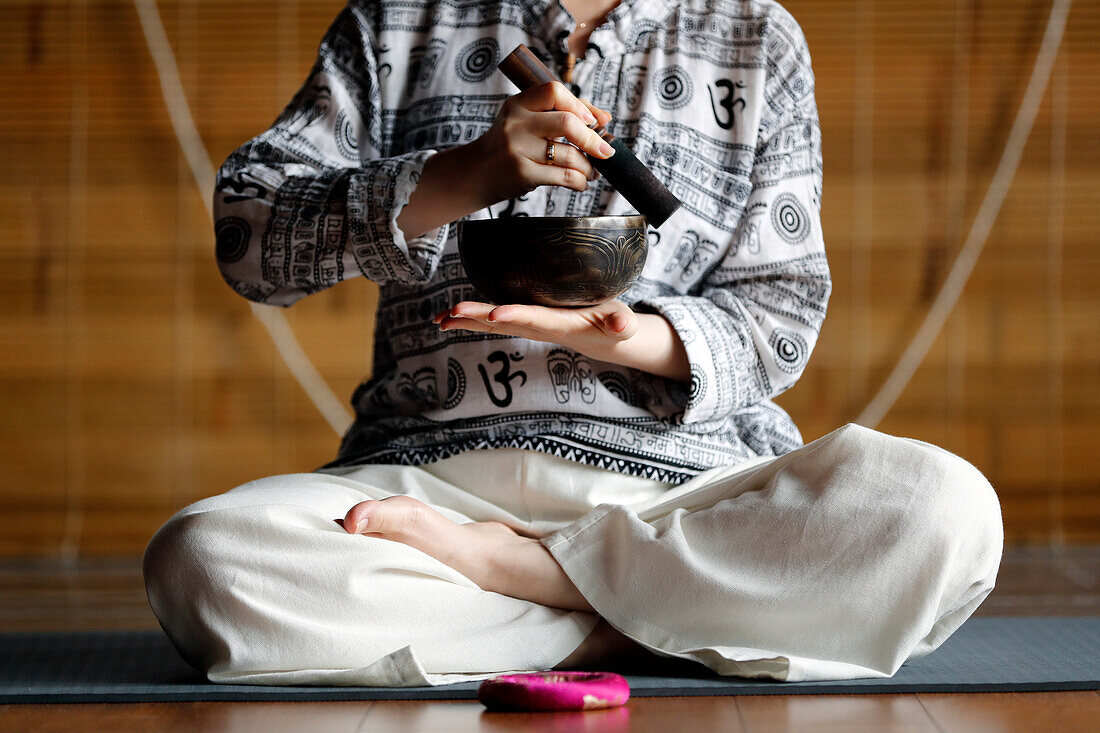 Tibetische Schale, buddhistische Frau, die eine Klangschale für die Klangtherapie in einer Atmosphäre der Heilung, Meditation, Yoga und Entspannung übt, Quang Ninh, Vietnam, Indochina, Südostasien, Asien