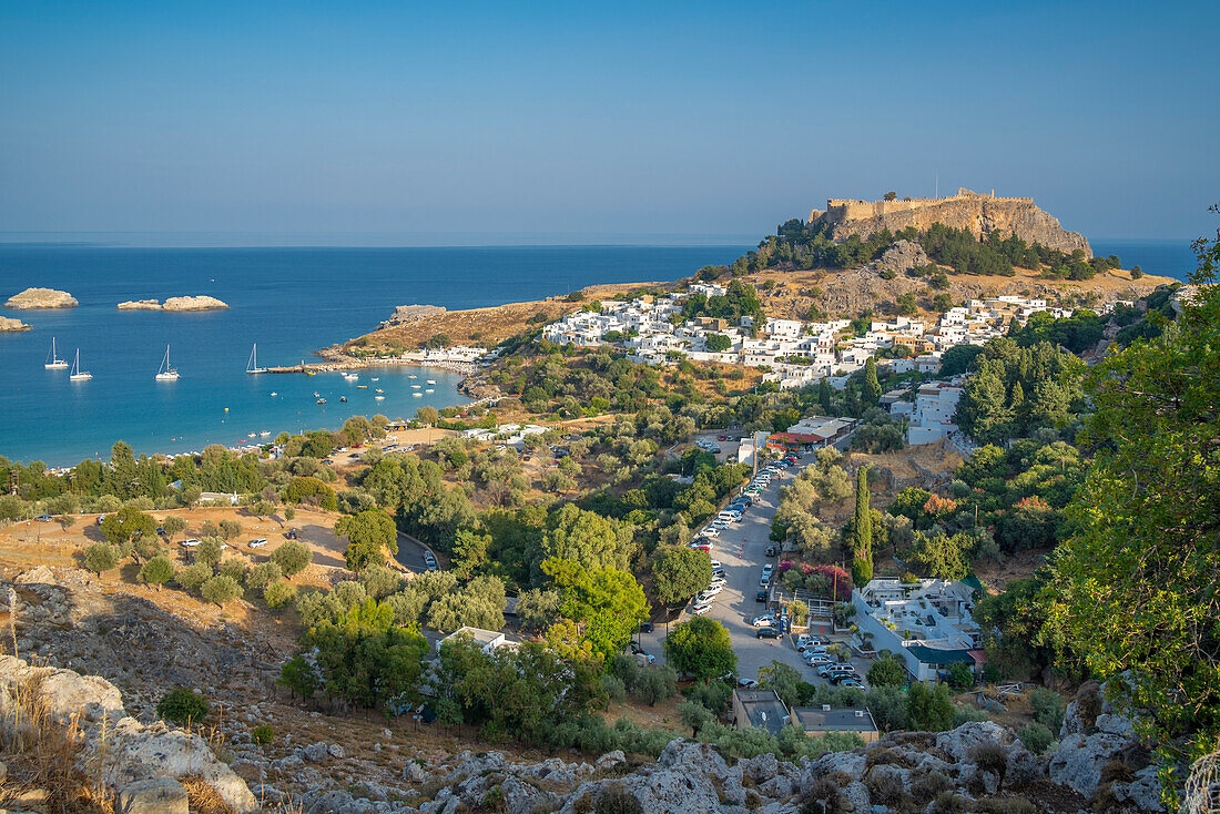 Blick auf Segelboote in der Bucht, Lindos und Lindos Akropolis von erhöhter Position, Lindos, Rhodos, Dodekanes Inselgruppe, Griechische Inseln, Griechenland, Europa