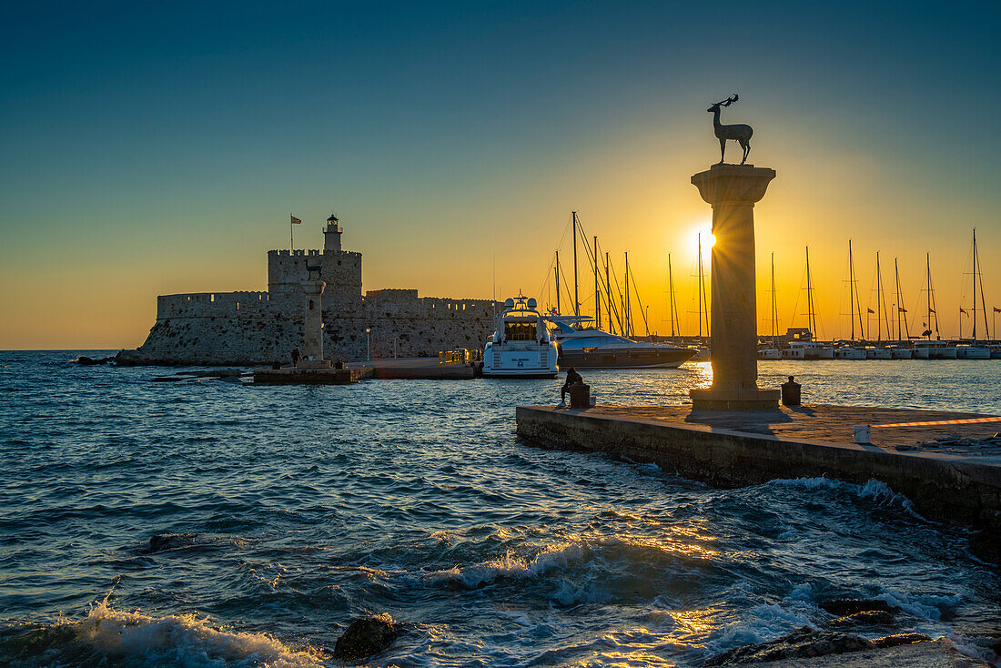 Blick auf bronzene Hirsch- und Reh-Statuen und die Festung des Heiligen Nikolaus bei Sonnenaufgang, UNESCO-Welterbe, Stadt Rhodos, Rhodos, Dodekanes, Griechische Inseln, Griechenland, Europa