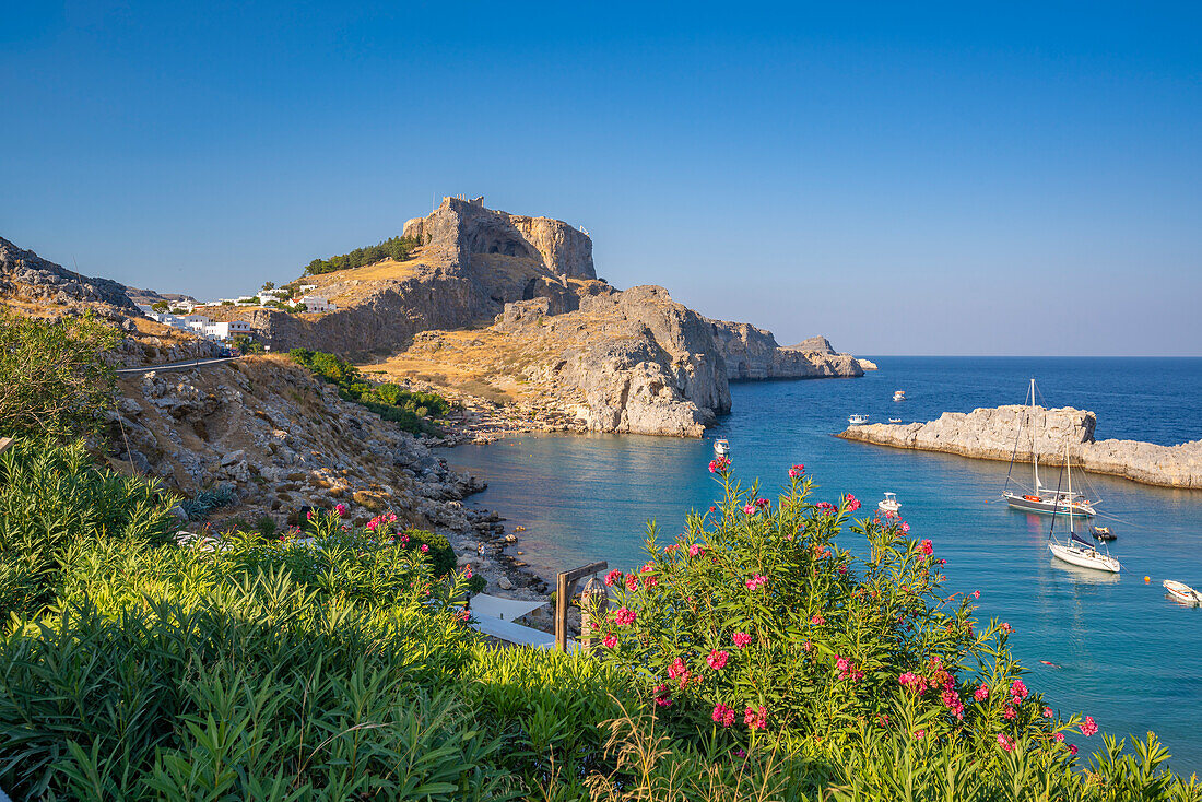 Blick auf Segelboote in der Bucht, Lindos und Lindos Akropolis von erhöhter Position, Lindos, Rhodos, Dodekanes Inselgruppe, Griechische Inseln, Griechenland, Europa