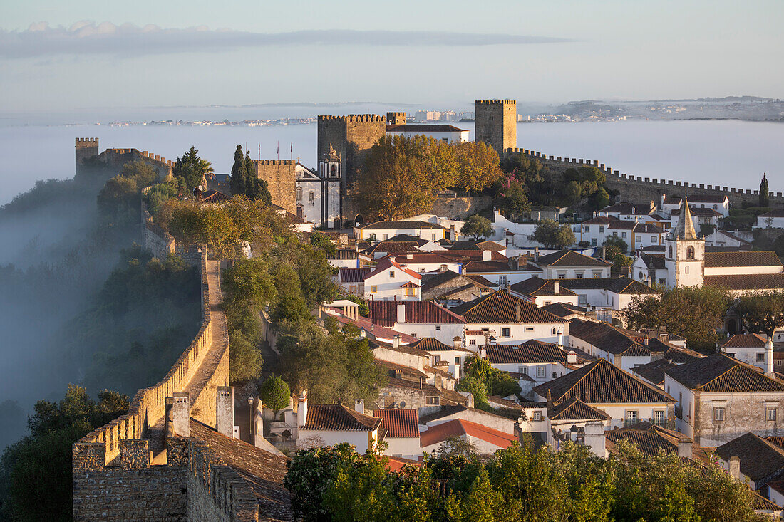 View over the old town and walls of Obidos in morning mist, Obidos, Centro Region, Estremadura, Portugal, Europe