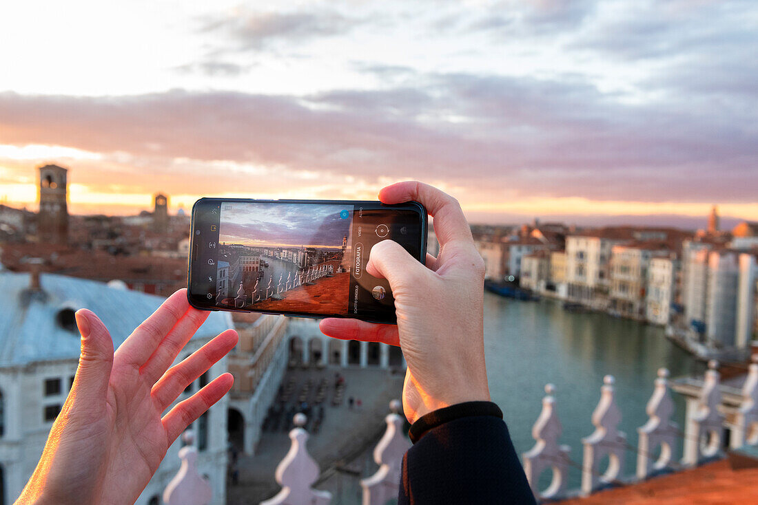 Die Hände einer Frau, die den Sonnenuntergang in Venedig mit dem Handy fotografiert, Venedig, Venetien, Italien, Europa