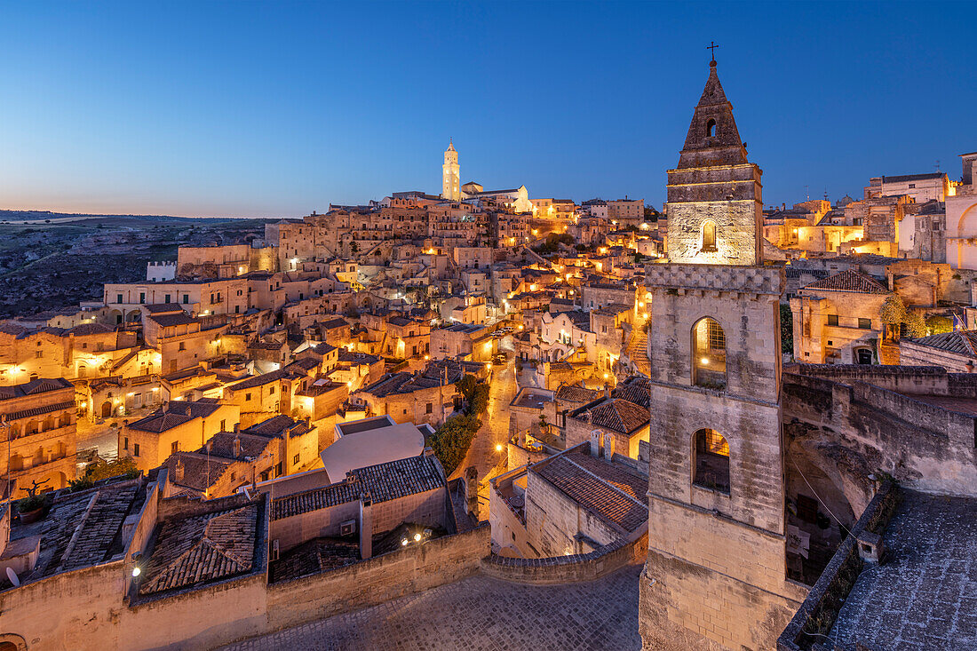 Blick über die Altstadt von Sassi di Matera mit dem in der Morgendämmerung beleuchteten Glockenturm der Kirche San Pietro Barisano, UNESCO-Weltkulturerbe, Matera, Basilicata, Italien, Europa