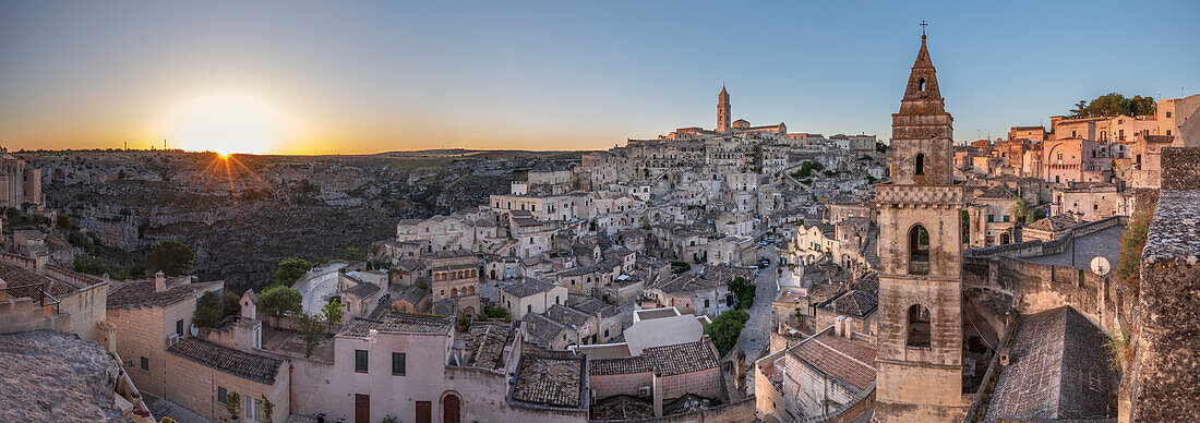 Sun rising over the canyon and Sassi di Matera old town with the campanile of the church of Saint Peter Barisano, UNESCO World Heritage Site, Matera, Basilicata, Italy, Europe