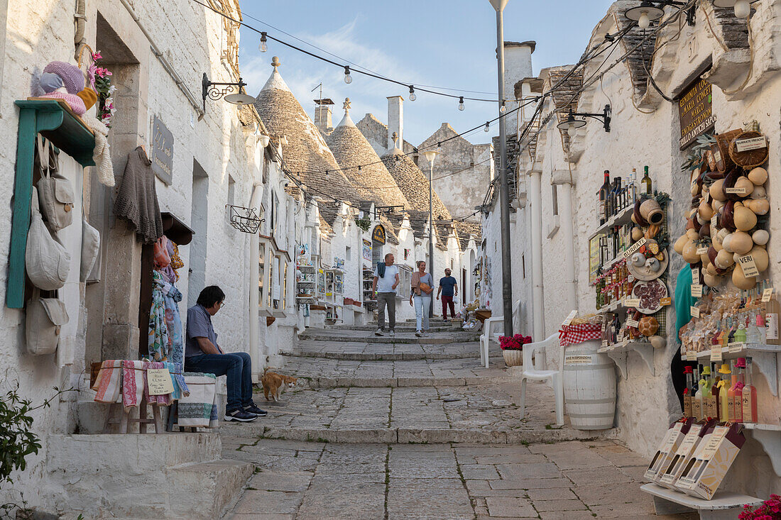 Weiß getünchte Trulli-Häuser und Souvenirläden entlang der Straße in der Altstadt, Alberobello, UNESCO-Weltkulturerbe, Apulien, Italien, Europa