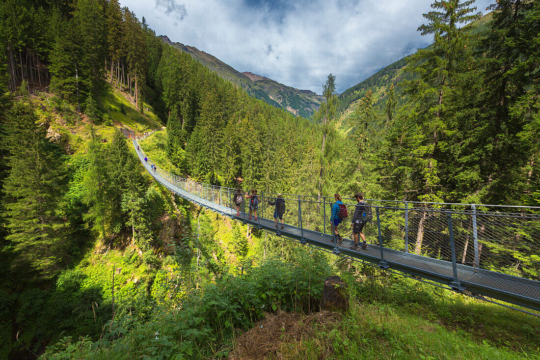 People cross the tibetan bridge (Ponte Sospeso Ragaiolo), Rabbi valley (val di Rabbi), Trento province, Trentino-Alto Adige, Italy, Europe