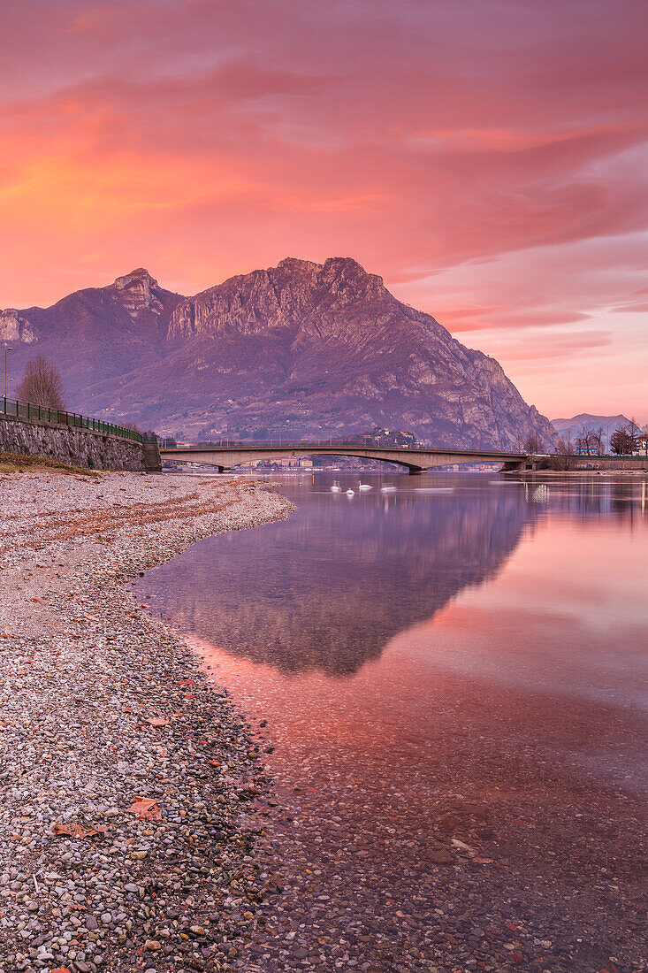 Sunrise on Lecco mountains (Moregallo, Corni di Canzo) reflected into the Adda River, Lecco city, lake Como, Lombardy, Italy, Europe