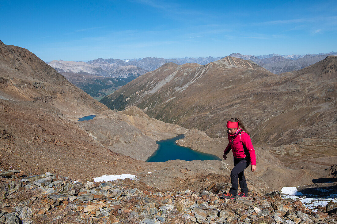 A girl is walking in Val Nera and in background lakes of Mine, Livigno, Sondrio Province, Valtellina, Lombardy, Italy, Europe