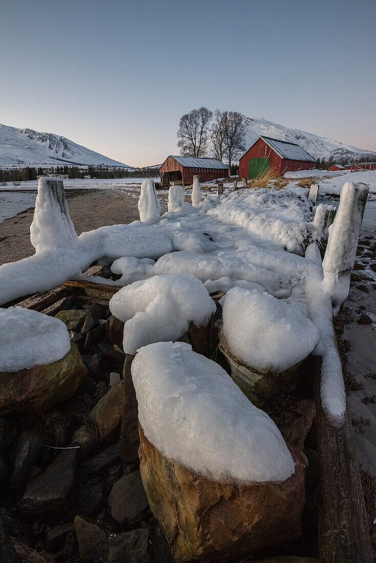 Typische Fischerhäuser vor einem Fjord in der Nähe von Tromso, Provinz Troms, Norwegen, Europa
