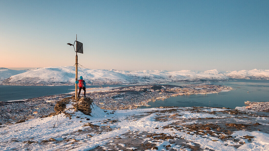 Mann bewundert die Stadt Tromso in der Abenddämmerung vom Berggipfel aus, Provinz Troms, Nordnorwegen, Europa