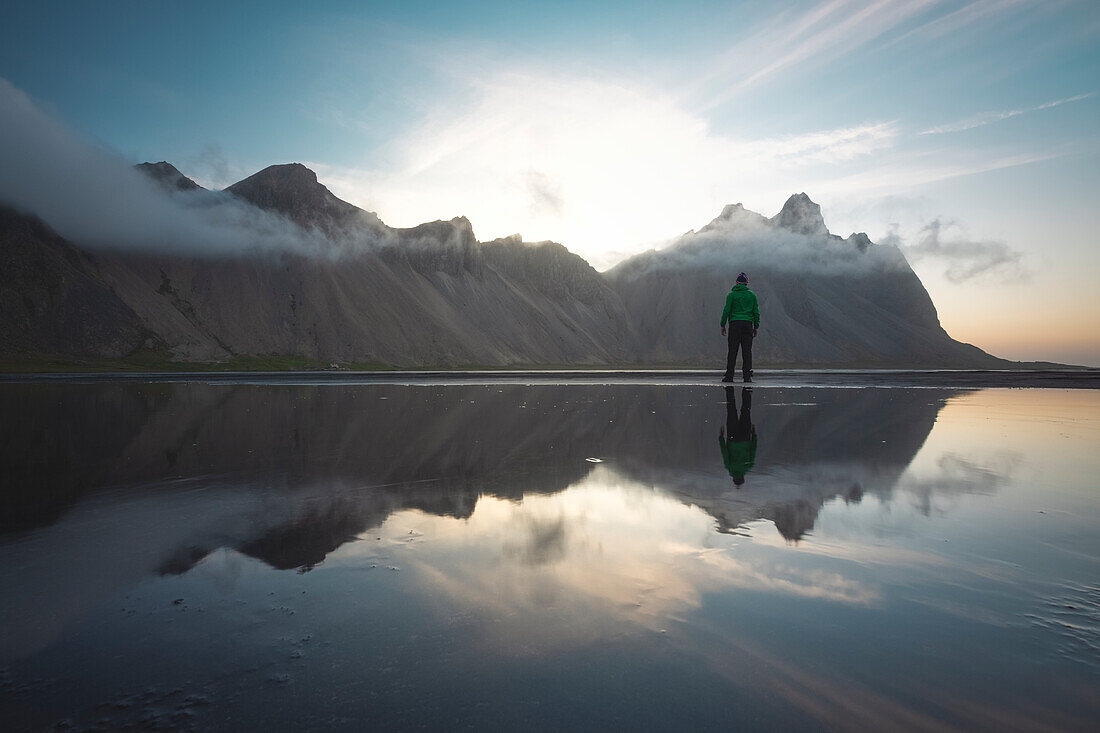 ein Mann bewundert das Vestrahorn während eines Sonnenaufgangs, Stokksnes, Hofn, Ostisland, Island, Europa.