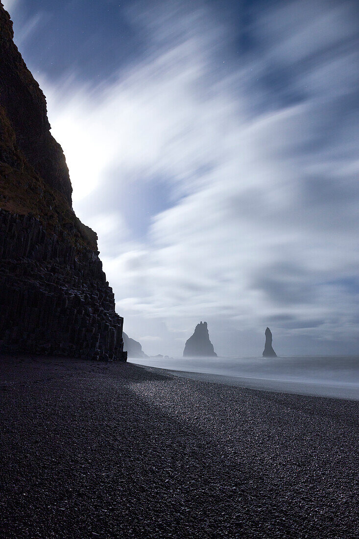 die Schornsteine von Vik i Myrdal, vom Reynisfjara-Strand aus gesehen, beleuchtet vom Mondlicht, Südisland, Europa