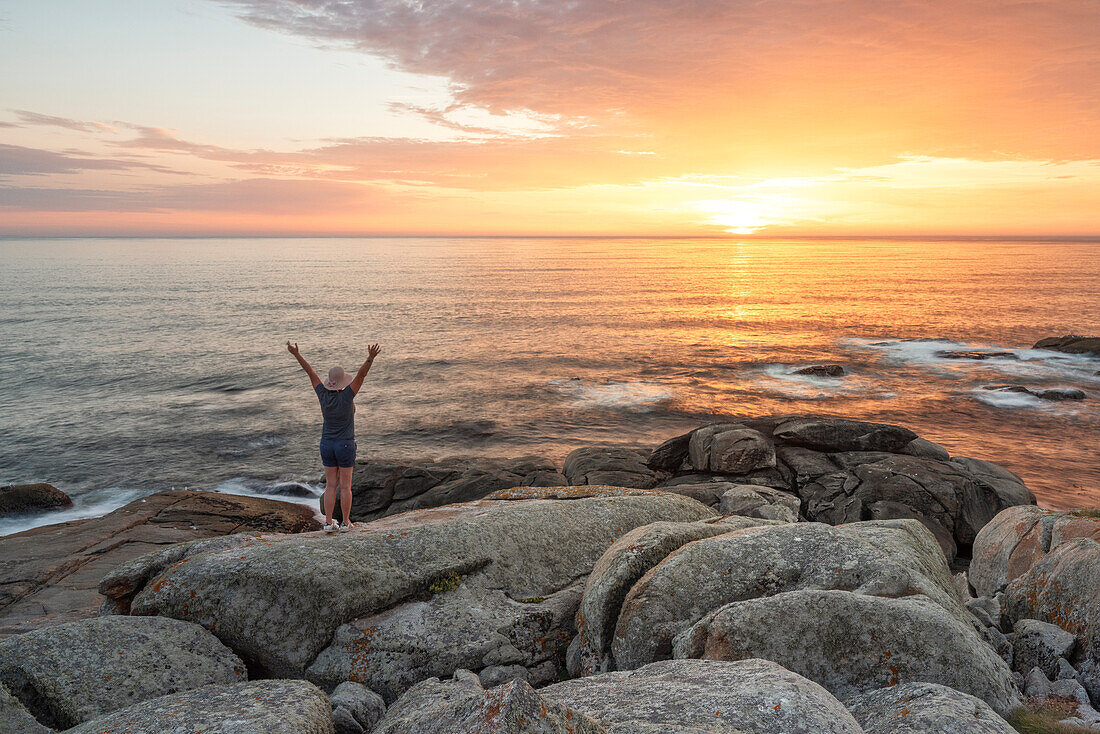 A tourist enjoy the summer sunset near to Santuario de Virxe da Barca, municipality of Muxia, Galixia, Spain, Europe