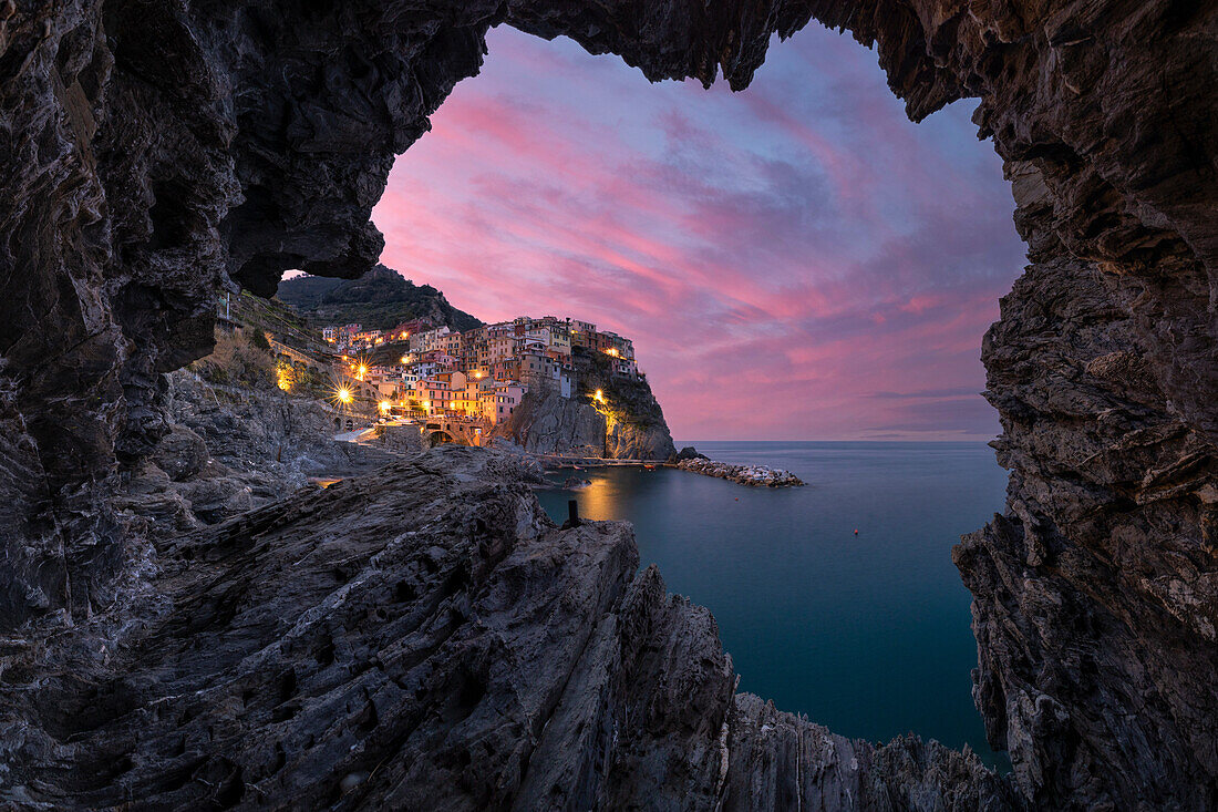 an amazing warm sunset at Manarola, catpured from a little cave, municipality of Riomaggiore, National Park of Cinque Terre, La Spezia province, Liguria district, Italy, Europe