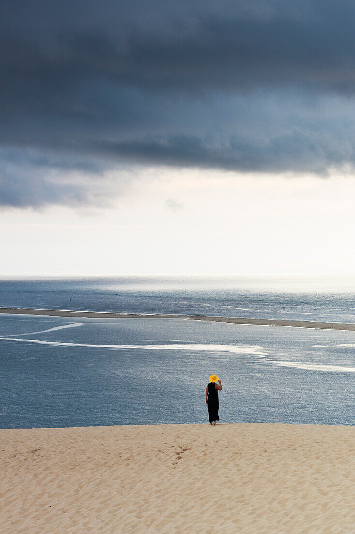 ein Tourist genießt den bewölkten Sonnenuntergang an der malerischen Dune du Pilat, Gemeinde La Teste-de-Buch, Frankreich, Europa