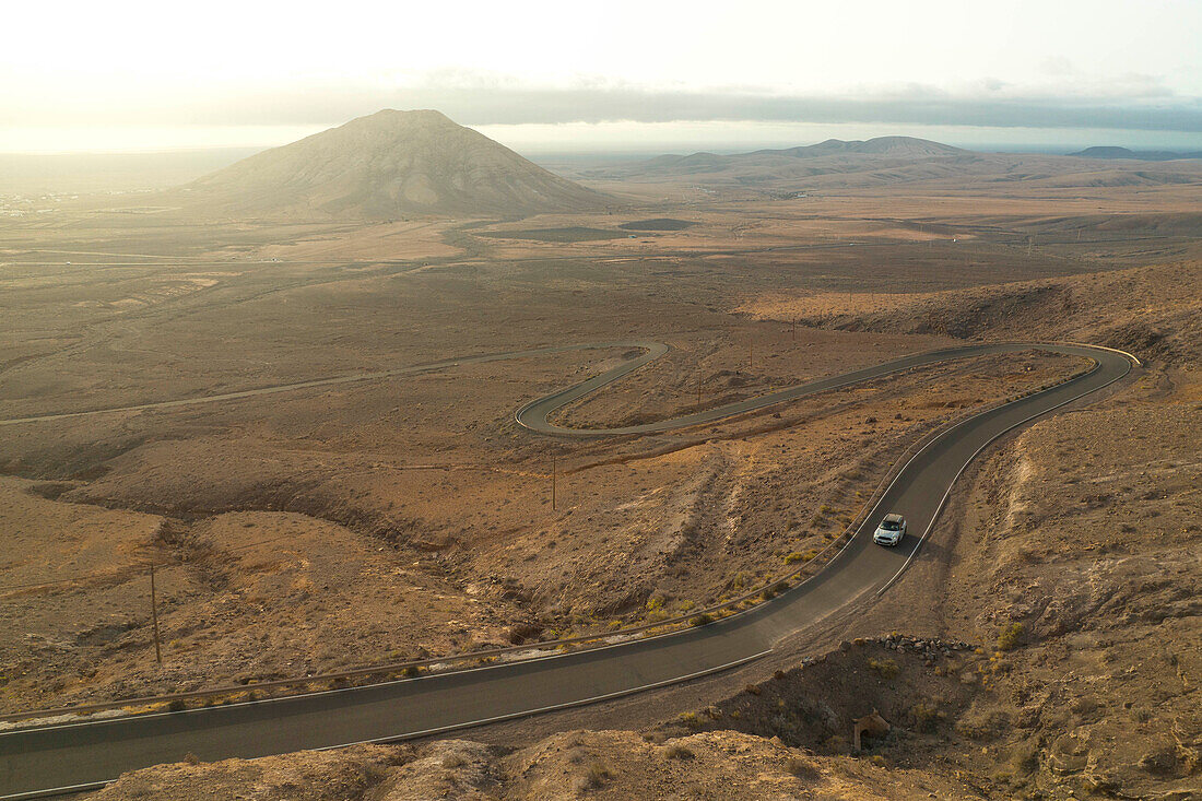 das warme Licht umhüllt die Straße in der Nähe des Berges Tindaya während eines Sonnenuntergangs im Sommer, Fuerteventura, Kanarische Insel, Spanien, Europa